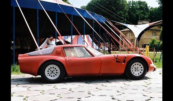 This Alfa Romeo TZ2 was developed directly by Autodelta, the Racing arm of Alfa Romeo, in 1965. Under a glass fibre reinforced composite body there is a tubular frame and a four cylinder 1570 cc engine which developed 170 hp at 7.500 rpm. The top speed is announced for 250 kph. The TZ2 is an evolution of the TZ1 prepared by Zagato; it has a remodeled body and lower tubular frame.  lateral